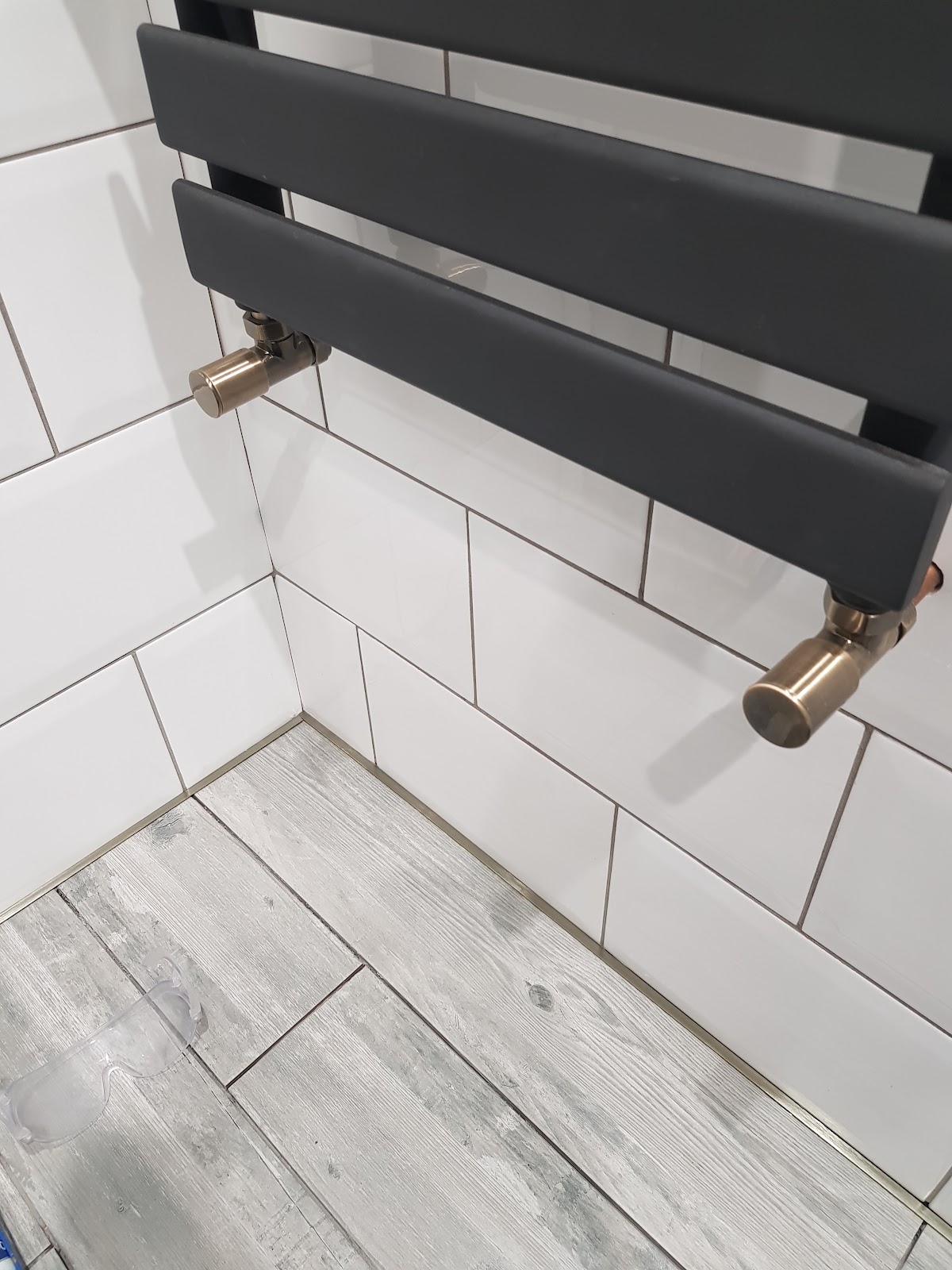 Close view of a fitted black towel radiator and tiled floor