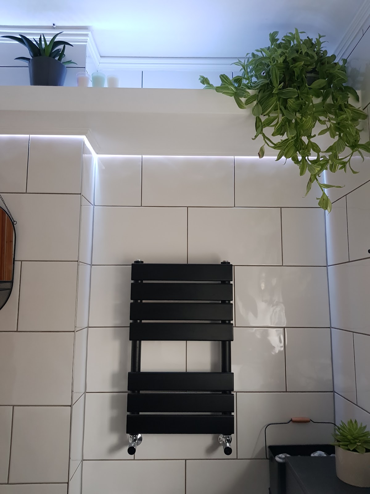 Finished white tiling with black radiator and concealed lighting